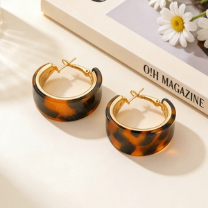 Close-up of leopard print hoop earrings with golden metal inner band on a soft background