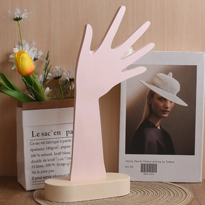 Dettaglio del supporto per gioielli a forma di mano rosa con solida base beige