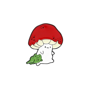 Gros plan d'un pin's en émail avec un champignon et une grenouille verte en alliage