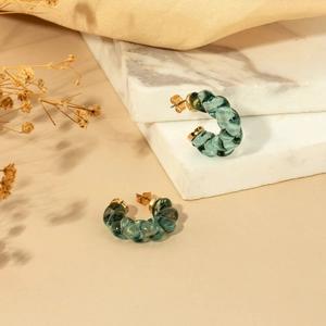 Dark green translucent twisted C-shaped earrings with gold studs on marble surface