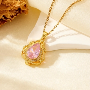 Elegant gold necklace with pink teardrop pendant on white stone and silk background