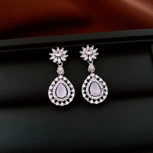 Macro view of silver flower and pink teardrop earrings with crystals on silk
