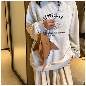 Detail of creative brown shark-shaped crossbody bag with silver chain strap and PU leather