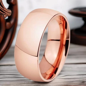 Close-up of polished 8mm rose gold stainless steel ring on a rustic wooden surface
