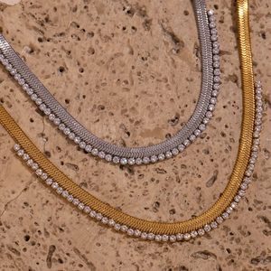 Macro shot of gold and silver herringbone chains with zircon crystals on stone