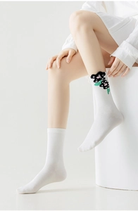 Detail of white mid-calf socks with black floral polka dots and elastic texture