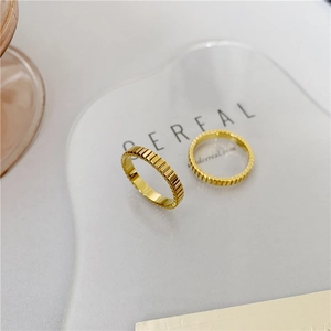 Detail of two gold plated titanium rings featuring vertical grooved texture design