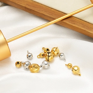 Golden and silver stainless steel bell pendants in various sizes on white silk fabric