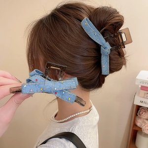 Detail of denim bow hair claw with colorful rhinestones on a brown resin base