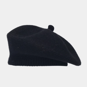 Detailed side view of a black knitted beret with a soft wool-like texture and top pompom