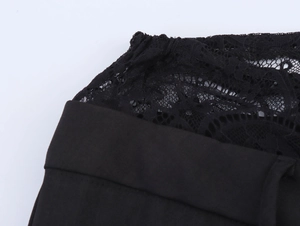 Close-up of the delicate lace splicing and textured fabric on black trousers