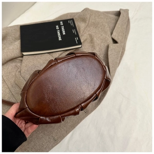 Detail of the brown ruched cloud bag showing the oval flat base and soft leather texture