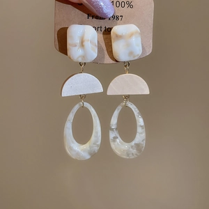 Detailed view of geometric resin wood drop earrings with marble pattern on a display card