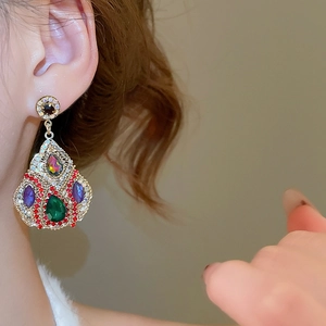 Close-up of bohemian dangling earrings with colorful zircon stones on model's ear