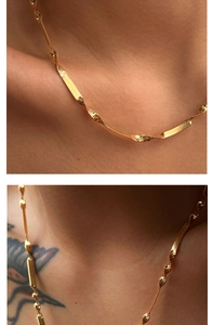 Detail of gold snake chain necklace with twisted blade texture on model neck