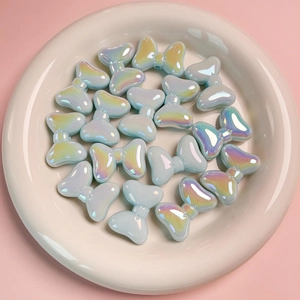 Iridescent blue bow-knot acrylic beads for DIY jewelry making in a white ceramic dish