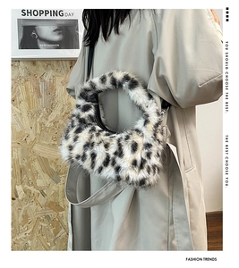 Detail of plush leopard print faux fur crescent bag with black shoulder strap worn by model