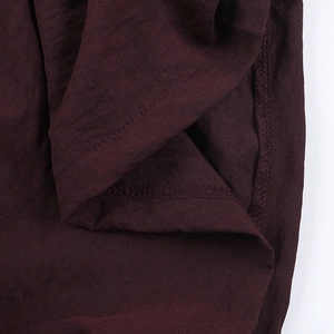 Detailed macro view of dark burgundy linen fabric showing the high quality sewing and texture