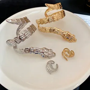 Irregular snake-shaped metal bracelet and ring set in polished gold and silver finishes