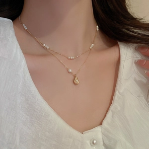 Close-up of double-layer gold necklace with baroque pearls worn by a model