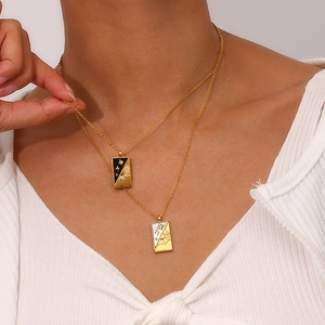Close-up of double layered gold necklaces with tarot star moon rectangular pendants