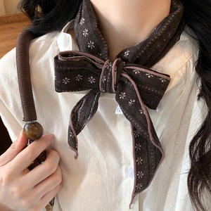 Close-up of a vintage dark brown floral cotton neckerchief tied in a bow over a white shirt