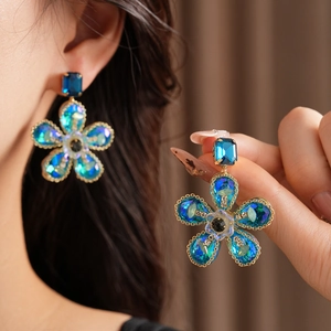 Gros plan sur les boucles d'oreilles fleur vintage avec cristaux bleus et cadre doré