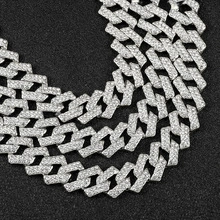 Macro shot of silver Cuban link chains with shimmering rhinestones on black background