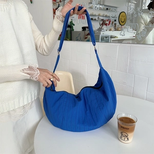 Detail of royal blue crescent crossbody bag with vertical quilted pleats and strap