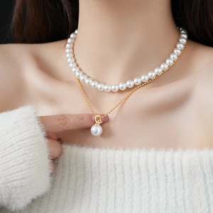 Detail of double-layer gold plated necklace with artificial pearls and letter D pendant