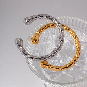 Minimalist hammer-textured 18K gold and silver stainless steel bangles set in ice