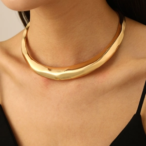 Close-up of a wide polished gold choker with a geometric wave design on a model