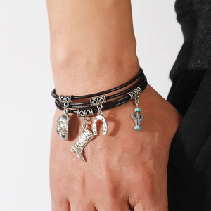 Close-up of multilayer leather bracelet featuring silver cowboy hat and horseshoe charms