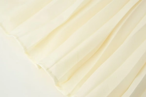Gros plan détaillé montrant la texture plissée dense du tissu en mousseline beige crème