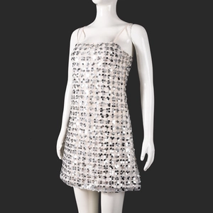 Détail d'une robe courte argentée à paillettes sur mannequin avec fond noir élégant