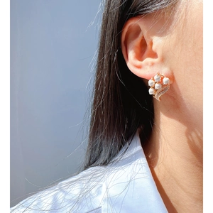 Elegant lily of the valley earrings with white enamel petals and gold base worn by model