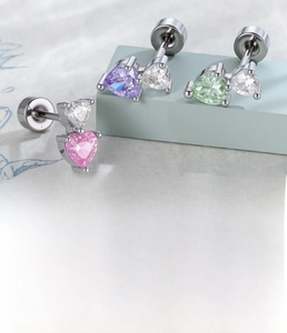 Detailed view of silver heart zircon cartilage studs in pink, purple and green tones