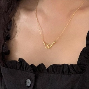 Minimalist gold necklace with abstract curve pendant on a black ruffled blouse