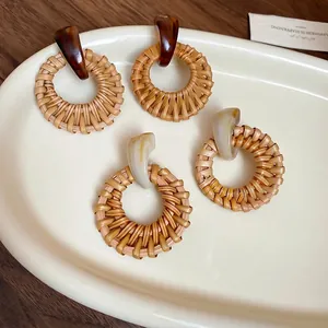 Retro geometric woven straw hoop earrings with resin studs on a wooden tray