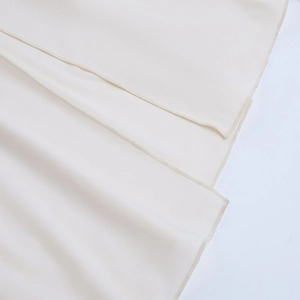 Detailed close-up of refined beige fabric layers with delicate stitching on the hem