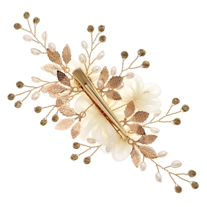 Detail of handmade fabric flower hair clip with pearls and rhinestones on a gold metal base