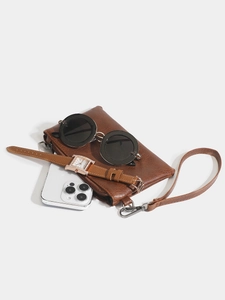 Litchi pattern leather clutch with wristlet, sunglasses, watch and phone on white backdrop