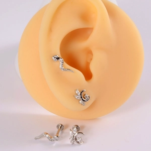 Macro detail of snake and moon flower ear studs with zircon on a realistic ear model