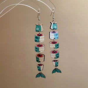Detailed close-up of fish-shaped pendant earrings with colorful prints and wood texture