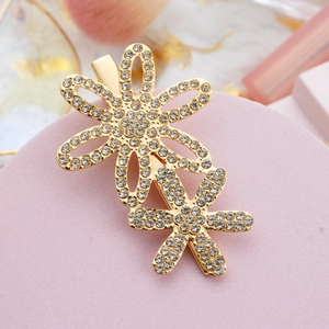 Detailed close-up of golden daisy hair clip with sparkling rhinestones on elegant background