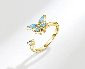 Macro view of golden butterfly open ring with blue crystals and clear stone detail