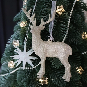 Sparkling champagne glitter reindeer and explosion star ornaments on a green Christmas tree