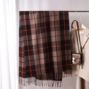 Detail view of plaid cashmere feel scarf with fringe tassels in cozy winter lifestyle setting