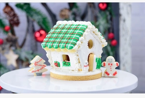 Close-up of 3D Christmas gingerbread house and tree cookies on a white cake stand