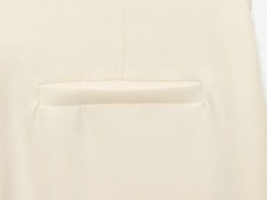 Vue macro des coutures de la poche et du tissu crème lisse sur l'ensemble tailleur